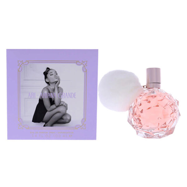Ariana Grande Ari Eau De Parfum for Women 3.4oz features a faceted pink bottle with a white pom-pom, paired with a lavender box showcasing Ariana’s photo—perfectly embodying this floral fruity fragrance from Ariana Grande.